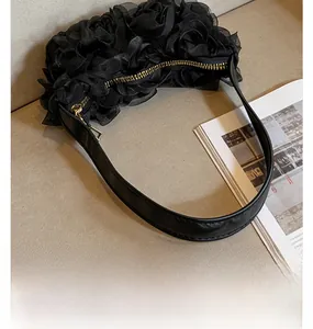 Détail de fleurs en maille 3D et d'une bandoulière en cuir sur un sac à main noir chic