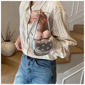 Détail du sac à bandoulière argenté avec nœud rose et dentelle pour enfant