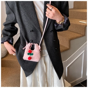 Detailed macro view of pink plush cherry crossbody bag featuring lamb wool texture