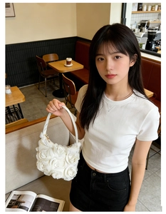 Détail d'un sac à main blanc orné de roses en tissu 3D aux textures élégantes