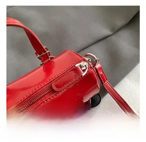 Gros plan d'un sac baril rouge brillant montrant les ferrures argentées et la couture