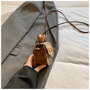 Detail of mini plaid crossbody bag with vintage leather bow and retro checkered fabric