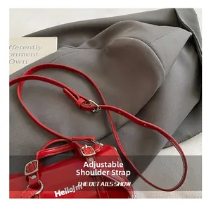 Détail du sac cylindre en cuir verni rouge avec bandoulière réglable et logo Hellojm