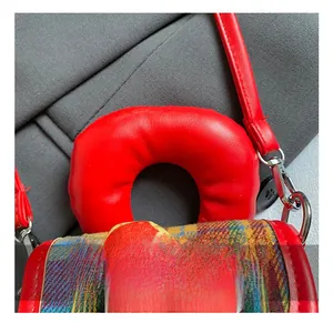 Détail de la poignée rouge rembourrée sur un sac à carreaux pour fille avec pendentif