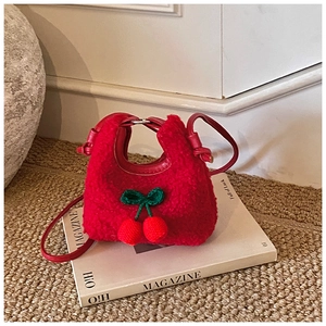 Close-up of red plush cherry handbag featuring 3D crochet detail on a magazine