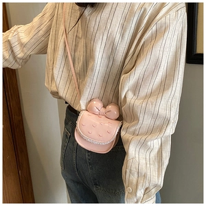 Détail du sac rose en cuir verni pour enfant avec nœud, cœur brodé et dentelle