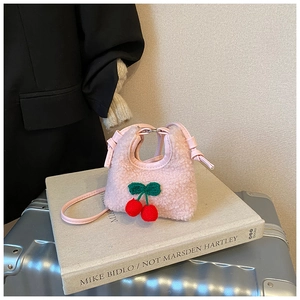 Detail of pink plush kids handbag featuring decorative woven cherries and faux leather handle