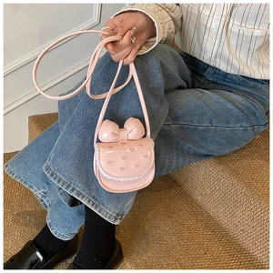 Détail du sac bandoulière en PU rose avec grand nœud, broderie cœur et bordure dentelle