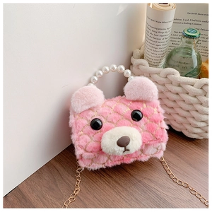 Detail of pink plush bear handbag featuring pearl handle and gold chain on wooden surface