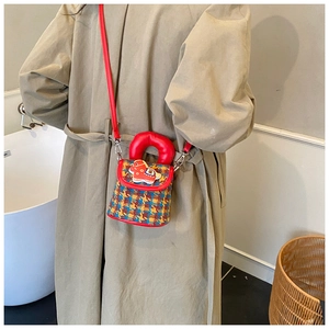 Détail d'un enfant portant un sac bandoulière à carreaux avec un patch poney rouge