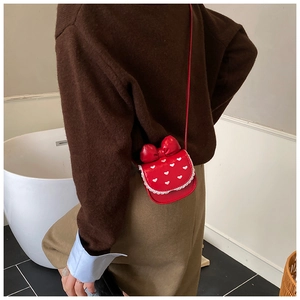 Vue latérale du petit sac rouge pour enfant avec nœud, motifs cœurs et dentelle