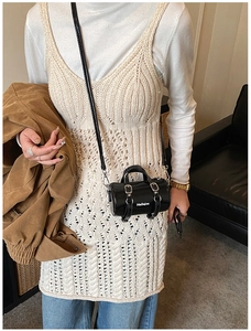Vue détaillée du sac cylindrique noir brillant porté sur une tenue de couleur beige