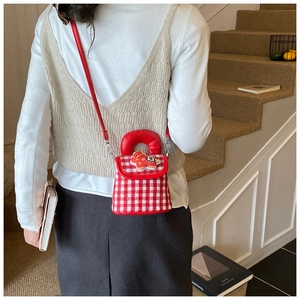 Détail d'un sac à carreaux rouges pour enfants avec écusson cheval porté par un enfant