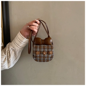 Detail view of mini plaid crossbody bag with brown leather bow and plush flower accents