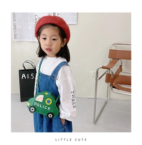 Detail shot of a small green car-shaped crossbody bag with Police text on a young girl