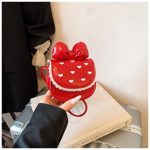 Détail d'un sac à bandoulière rouge en forme de cœur avec dentelle blanche et nœud
