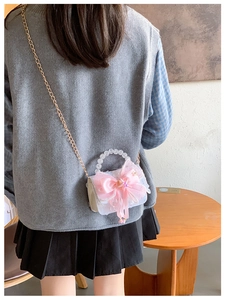 Détail d'un nœud en soie rose et poignée en perles sur sac en dentelle blanche