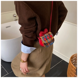 Detailed side view of a floral red plaid kids crossbody bag with a large bow decoration