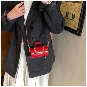 Gros plan d'un sac cylindrique rouge brillant avec inscription blanche et bandoulière