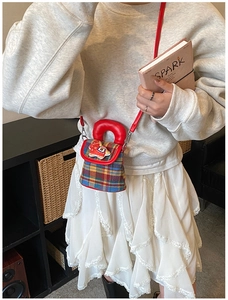 Détail du sac bandoulière en tweed à carreaux avec poignées rouges et breloque poney