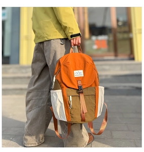 Outdoor street shot of a color-block kids backpack with MOUNTAINS logo and buckle straps