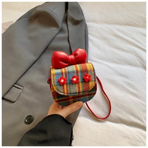Detailed view of British plaid kids bag with large red bow and 3D flower accents