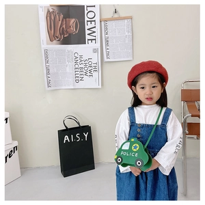 Detailed view of kids green car-shaped crossbody bag worn by a young child model