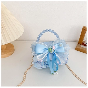 Détail du sac à paillettes bleu clair avec nœud en satin et anse en perles