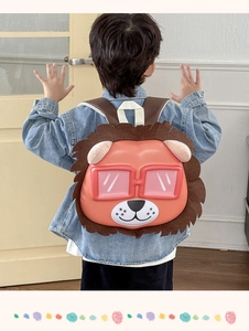 Rear view of child wearing a cute 3D orange lion cartoon eggshell backpack in home setting
