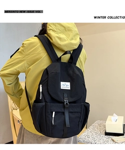 Close-up of black kids backpack featuring mountains logo and buckles on yellow jacket