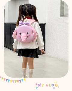 Pink plush elephant backpack with 3D ears and bow shown on a child model back