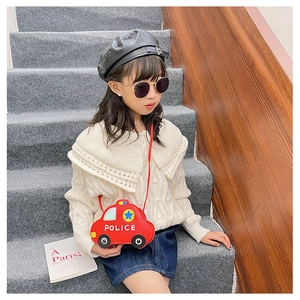Toddler in sweater wearing a red police car shaped crossbody bag on indoor stairs