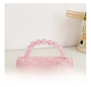 Detailed close-up of pink lace handbag featuring beaded handle and mesh bow decoration