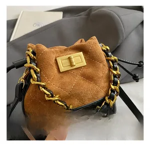 Detail of a brown quilted suede mini bucket bag featuring a gold metal turn-lock and chain
