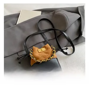 Close-up of quilted suede shoulder bag with gold twist lock and woven chain handle