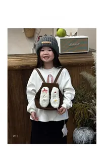 Detail of plush bunny ears and decorative bows on the brown kids backpack with star patches