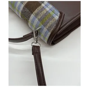 Detail of plaid fabric stitching with brown leather and premium silver metal hooks