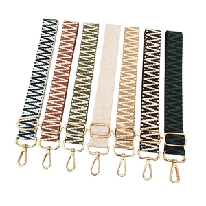 Detail of colorful woven geometric pattern bag straps with gold metal hooks and buckles