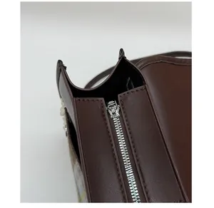 Detailed macro view of smooth silver metal zipper and stitching on dark brown leather bag