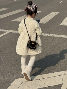 Close-up of a quilted black mini bag with gold chain strap on a stylish child's outfit