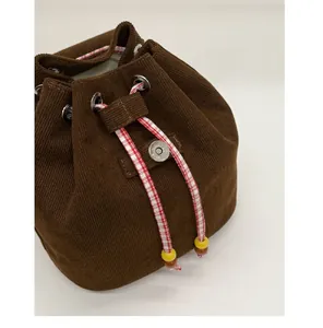 Detail of brown corduroy bucket bag showing drawstring closure and checkered rope