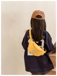 Detail of yellow kids fanny pack featuring a plush 'Y' letter patch on blue apparel