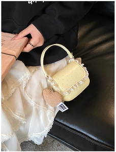 Détail du sac jaune à pois avec bordure en dentelle blanche et breloque cœur brun