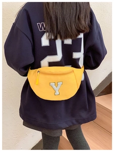 Detail view of a yellow canvas waist bag featuring a plush white letter Y patch for kids
