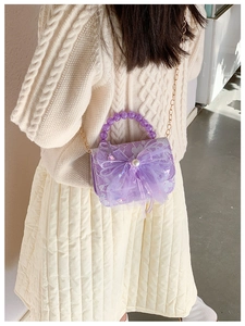 Detail of purple lace crossbody bag with mesh bow, pearl accents and beaded handle on a girl