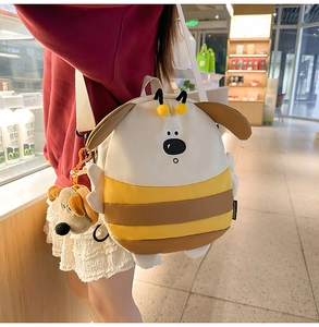 Detail view of a cute bee-themed striped canvas backpack with plush charm and soft strap