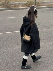 Detail of a kids black teddy coat and mini brown crossbody bag with gold chain strap