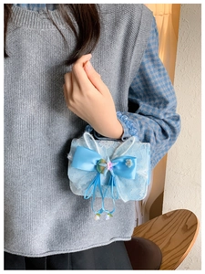 Detail of light blue lace girl's bag with a large satin bow and sea shell charms