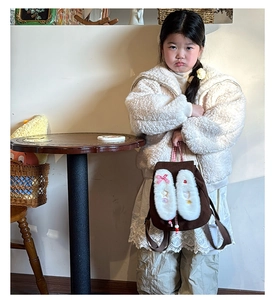 Close-up of brown children backpack featuring plush white rabbit ears and a bow