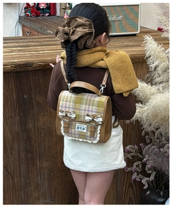 Detail of plaid children's backpack with cute bows and lace trim on a retro background
